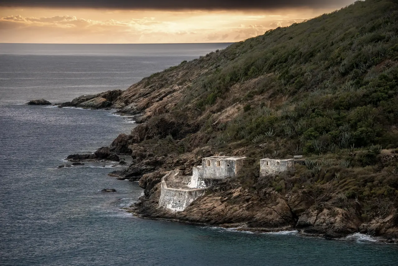 A sailboat leaving Charlotte Amalie at dusk, past the old fort ruins