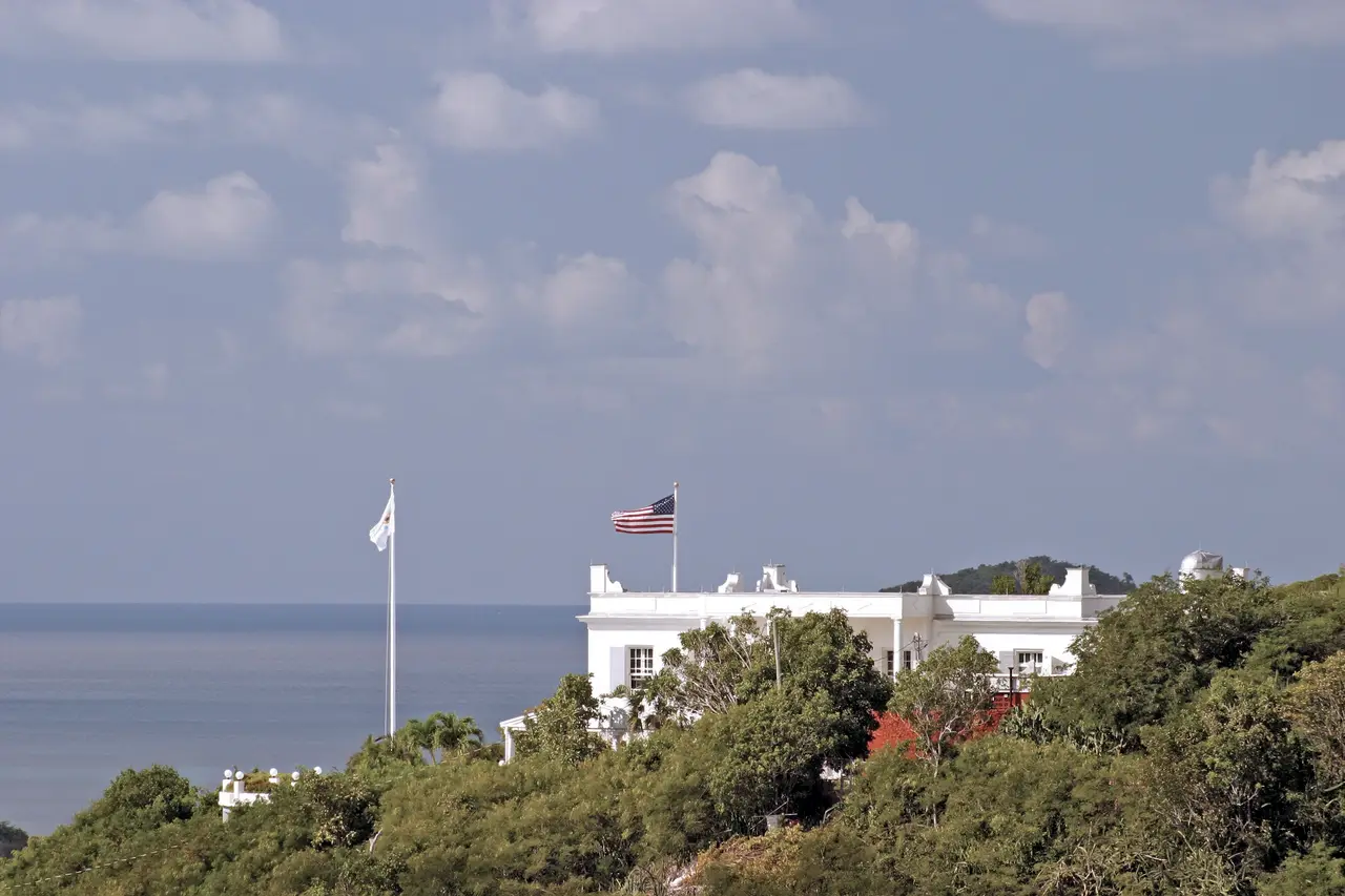 A white hilltop building flying the U.S. flag, the sea beyond